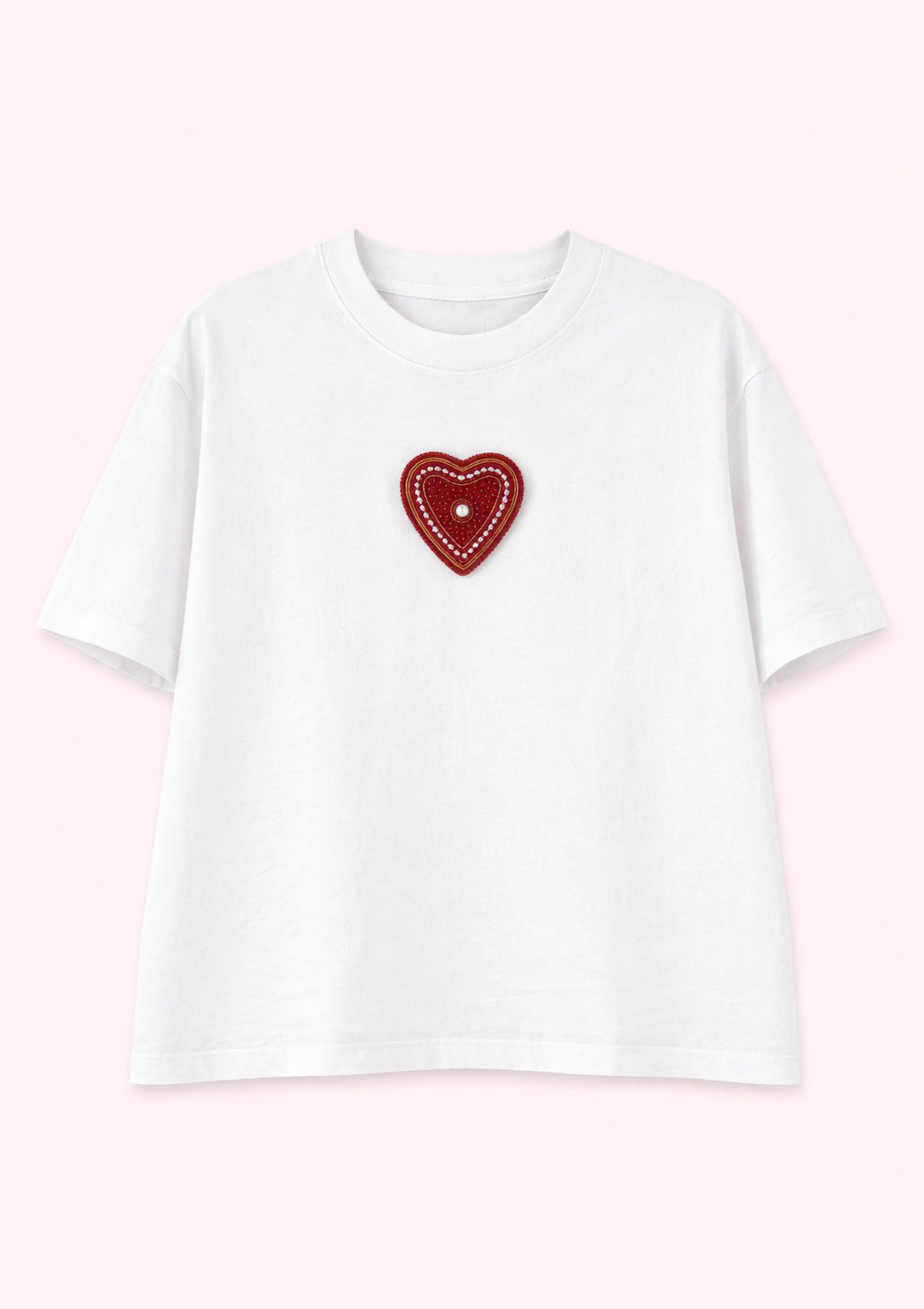 White t-shirt with a red heart-shaped patch on a light pink background