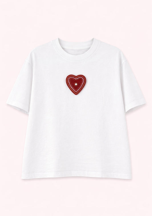 White t-shirt with a red heart-shaped patch on a light pink background