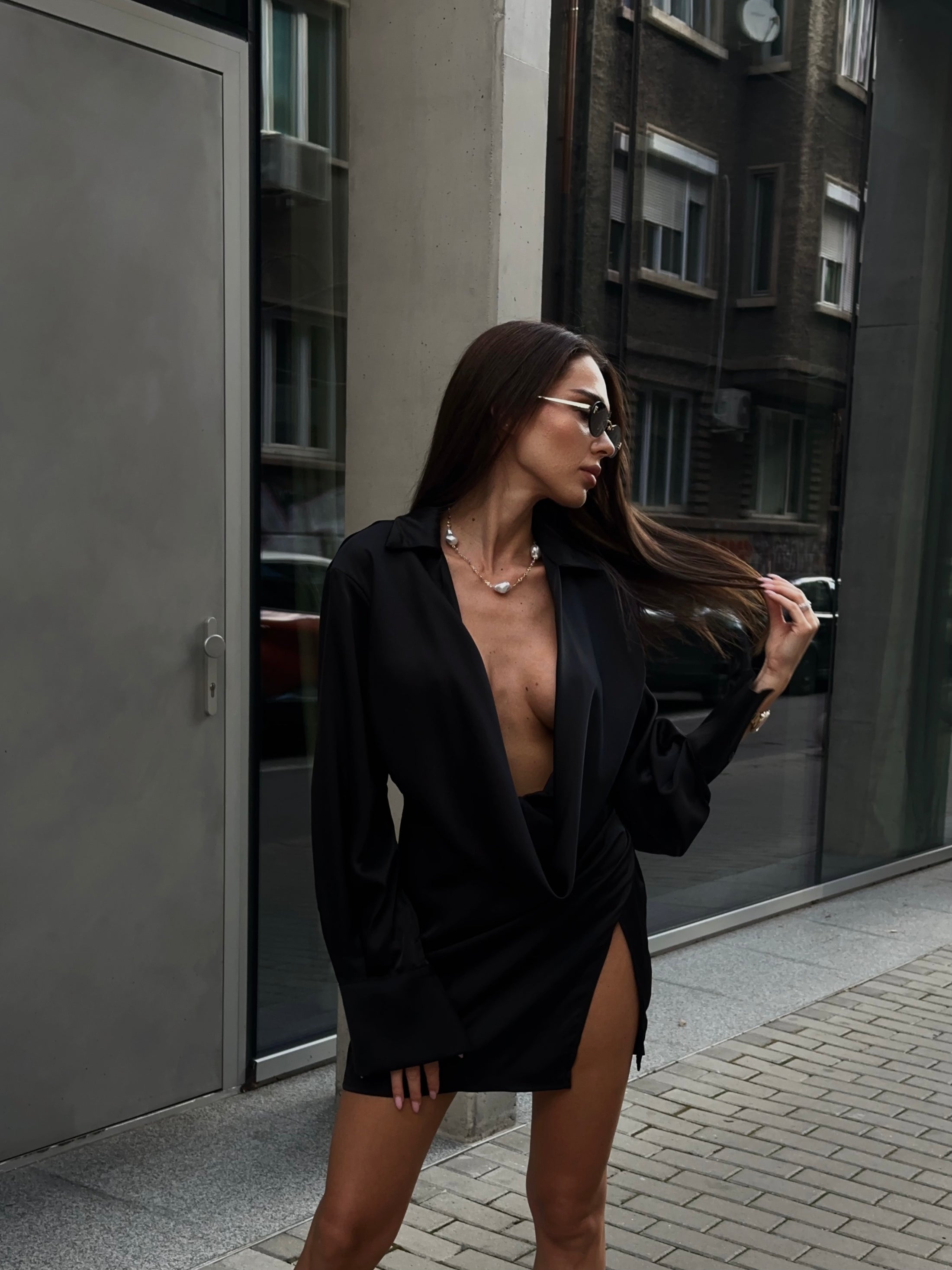 Woman in a black dress standing on a city street