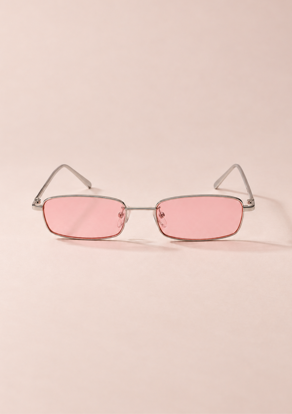 Rimless square sunglasses with pink tinted lenses and a thin silver metal frame, displayed on a solid pale pink background.