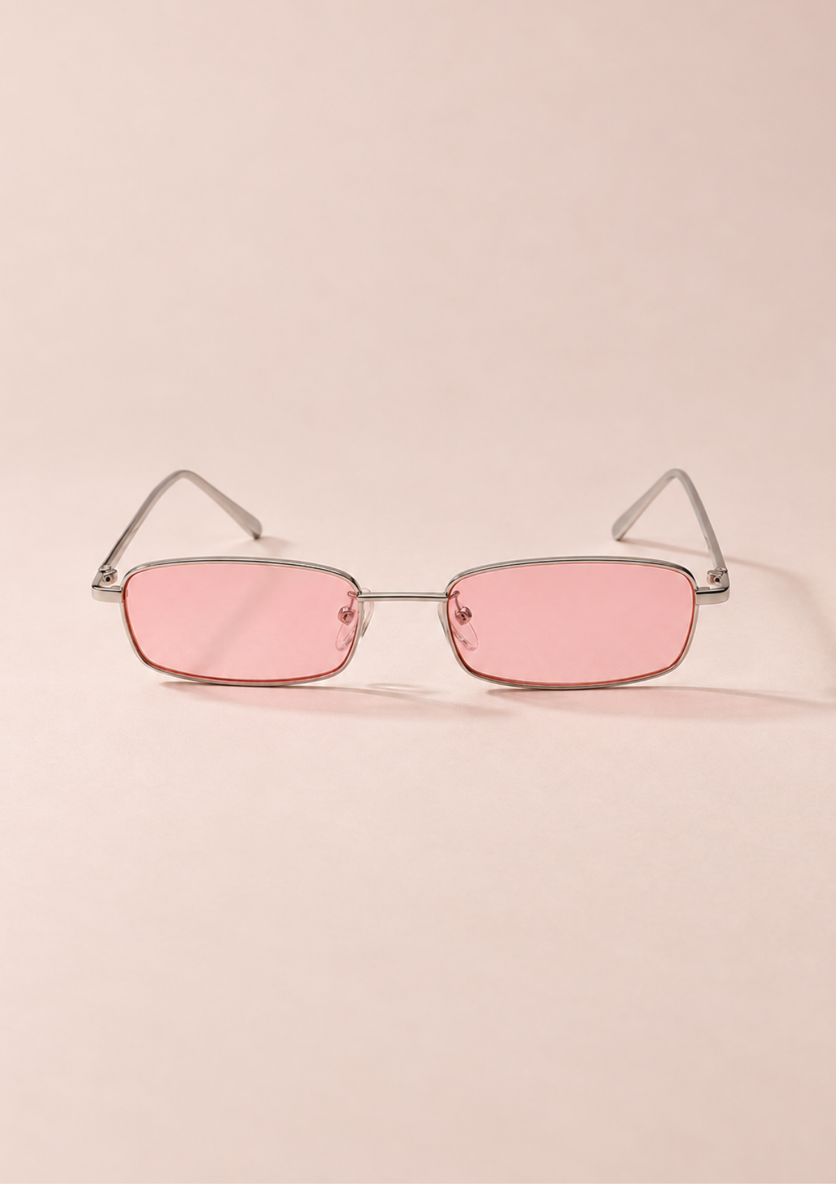 Rimless square sunglasses with pink tinted lenses and a thin silver metal frame, displayed on a solid pale pink background.