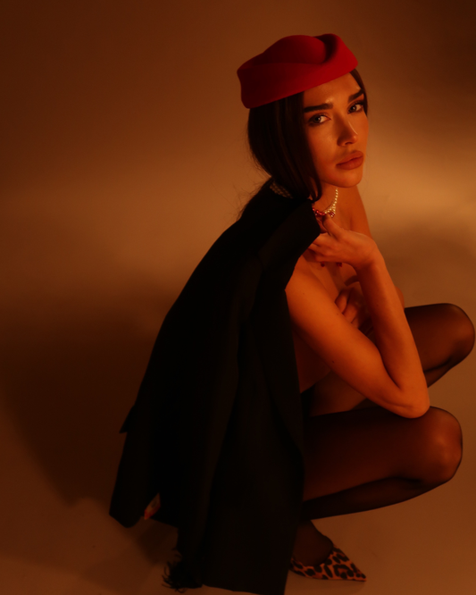 Woman wearing a red beret and black garment against a brown background