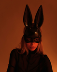 Заредете изображението в програмата за преглед на галерия, Person wearing a black bunny mask with pointed ears against an orange background
