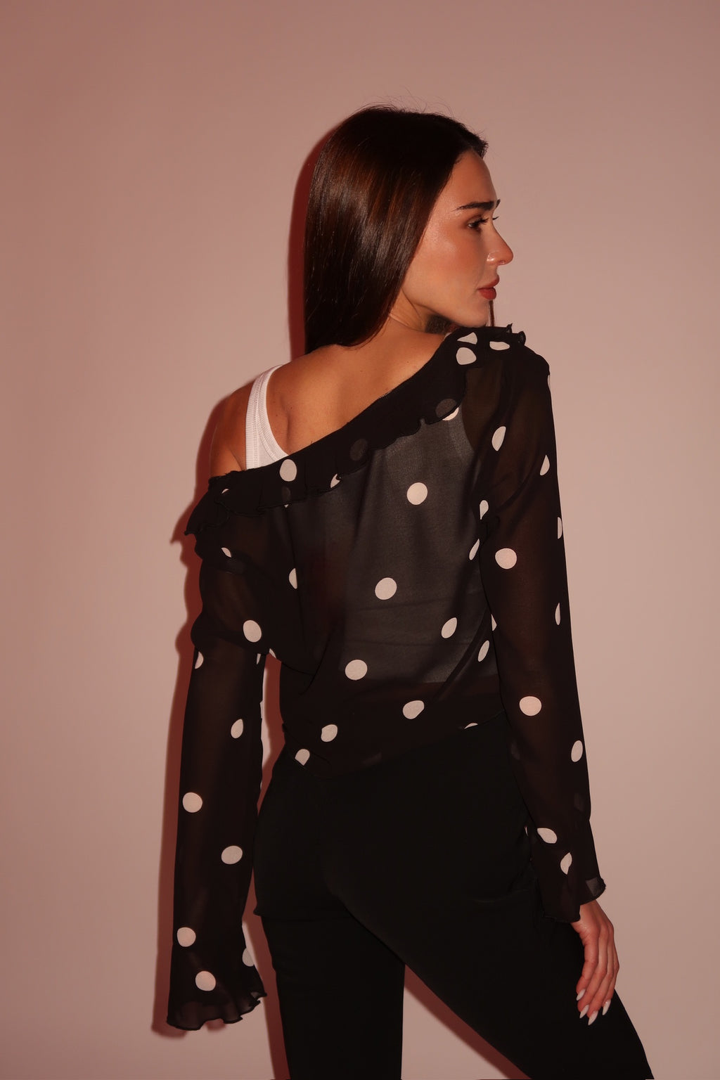 Woman wearing a black polka dot blouse with a plain background