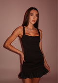 Load image into Gallery viewer, Woman wearing a black dress against a brown background
