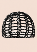 A black sequined mesh dome hat with an open lattice pattern, shown against a solid pale peach background.