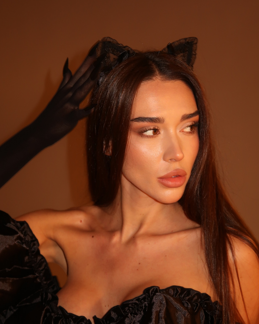 Woman wearing a black dress with cat ears against a brown background