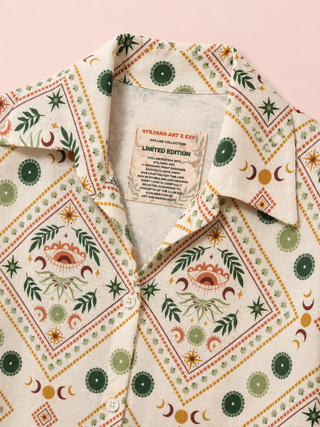 A close-up of a collared button-up shirt with a cream base and a detailed bohemian-style print featuring green, orange, and brown celestial motifs like crescent moons, stars, and eye designs. The inner collar label reads 'STYLANE ART X KIKI LIMITED EDITION'.