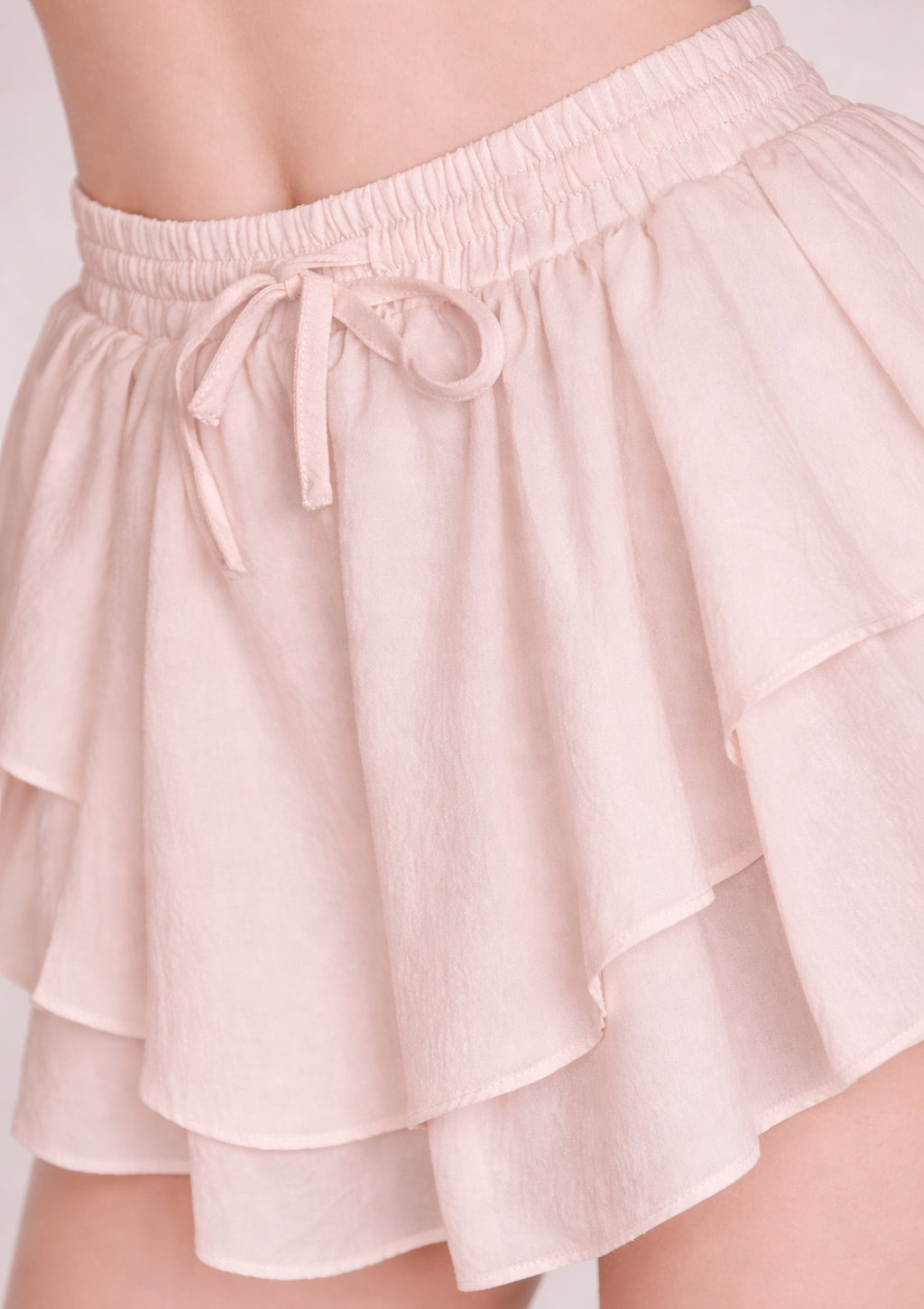 cream white ruffled shorts with a tie waist on a neutral background