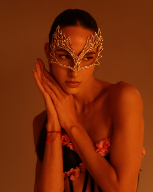 Woman wearing a decorative mask against an orange background