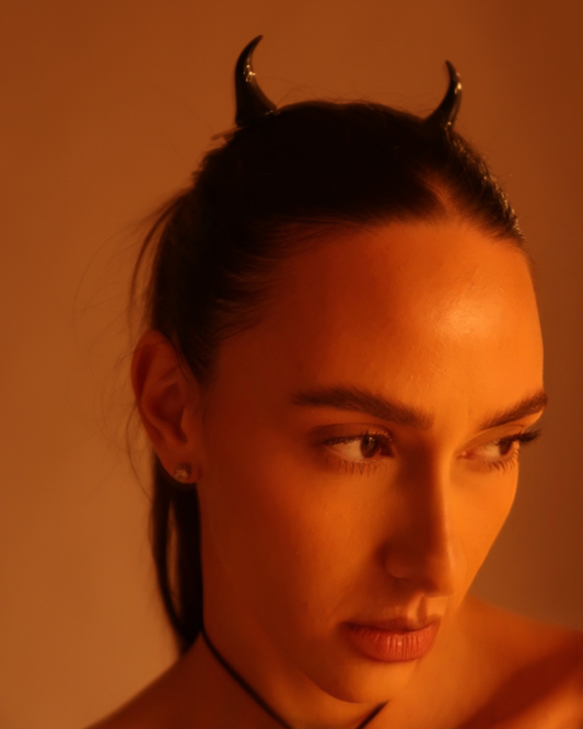 Person wearing devil horns hairpins with a warm, orange-toned light