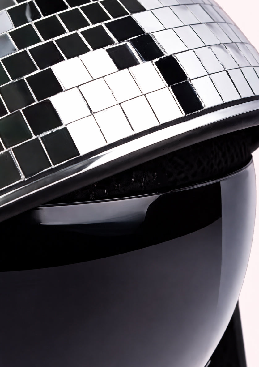 Close-up of a disco ball helmet with reflective black and silver tiles.