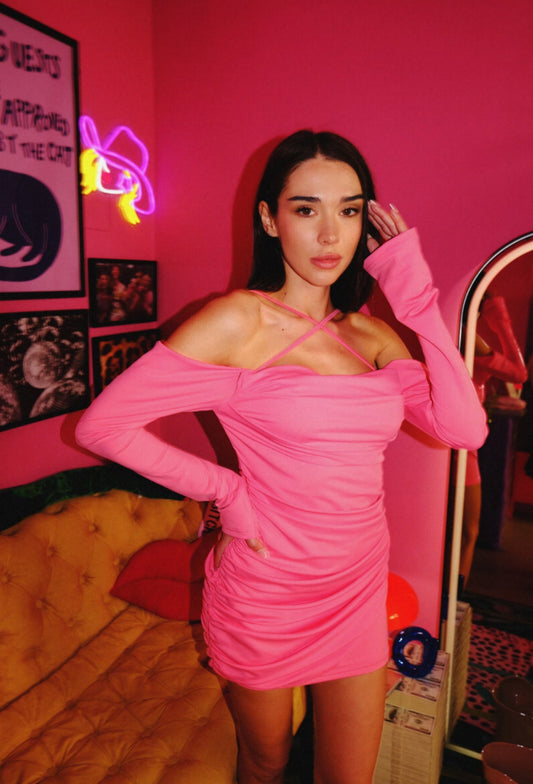 A person wearing a hot pink off-the-shoulder mini dress with ruched detailing and a criss-cross neckline.