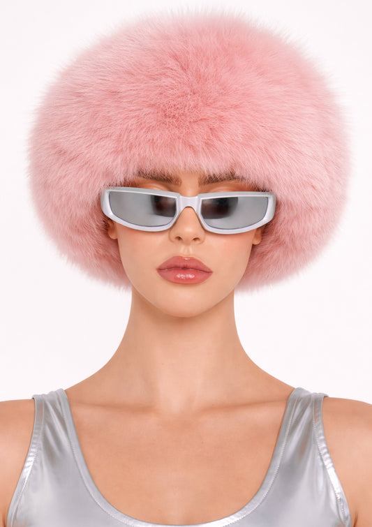 Person wearing a pink fur hat and silver sunglasses on a white background