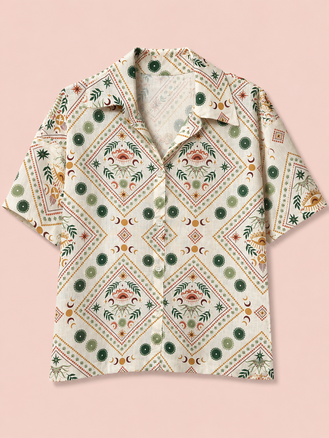 A short-sleeve button-up shirt with a bohemian-style geometric and floral pattern in green, orange, and brown on a cream background, displayed flat against a solid pale pink background.