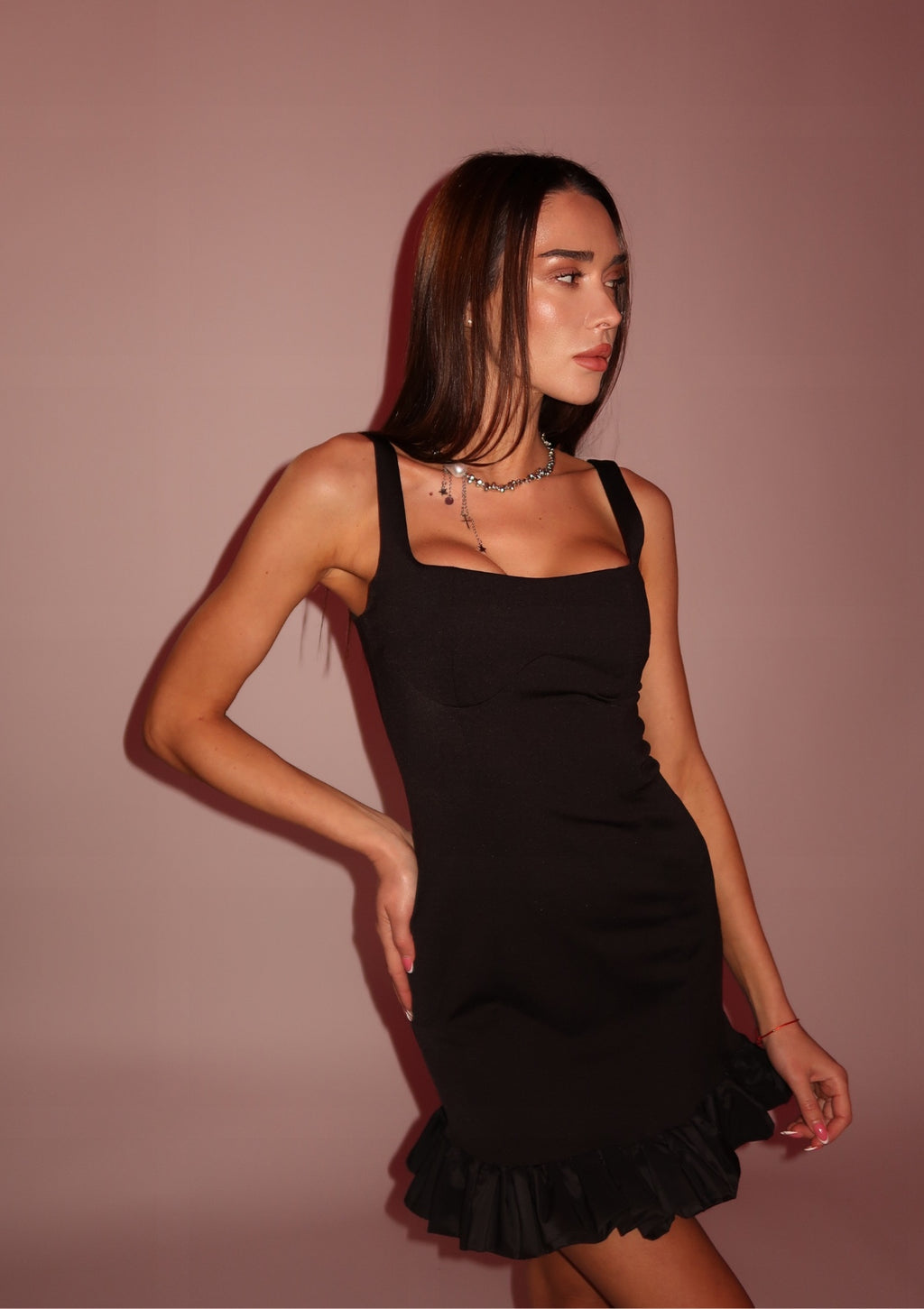 Woman wearing a black dress against a pink background