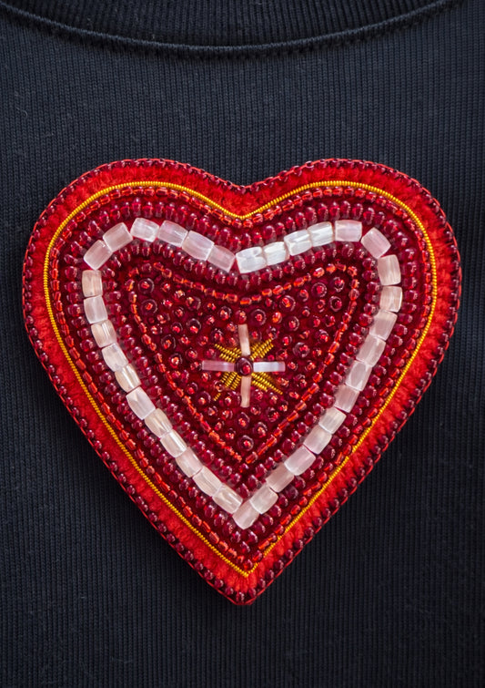 Red heart-shaped patch with beadwork on a dark background