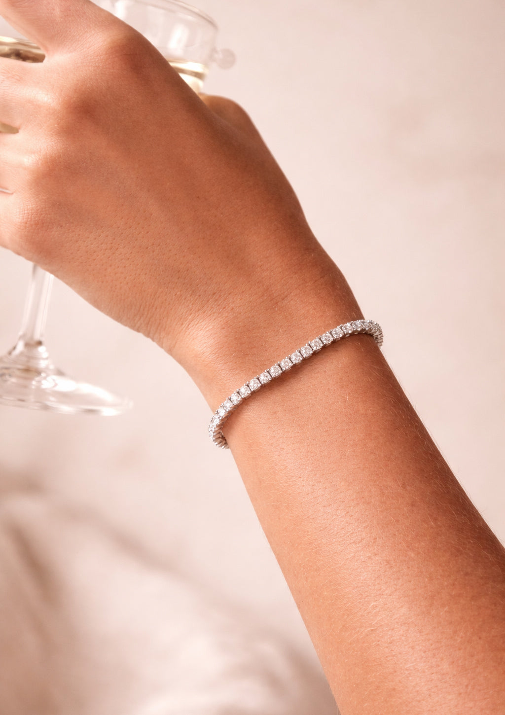 Hand wearing a silver bracelet on a plain background