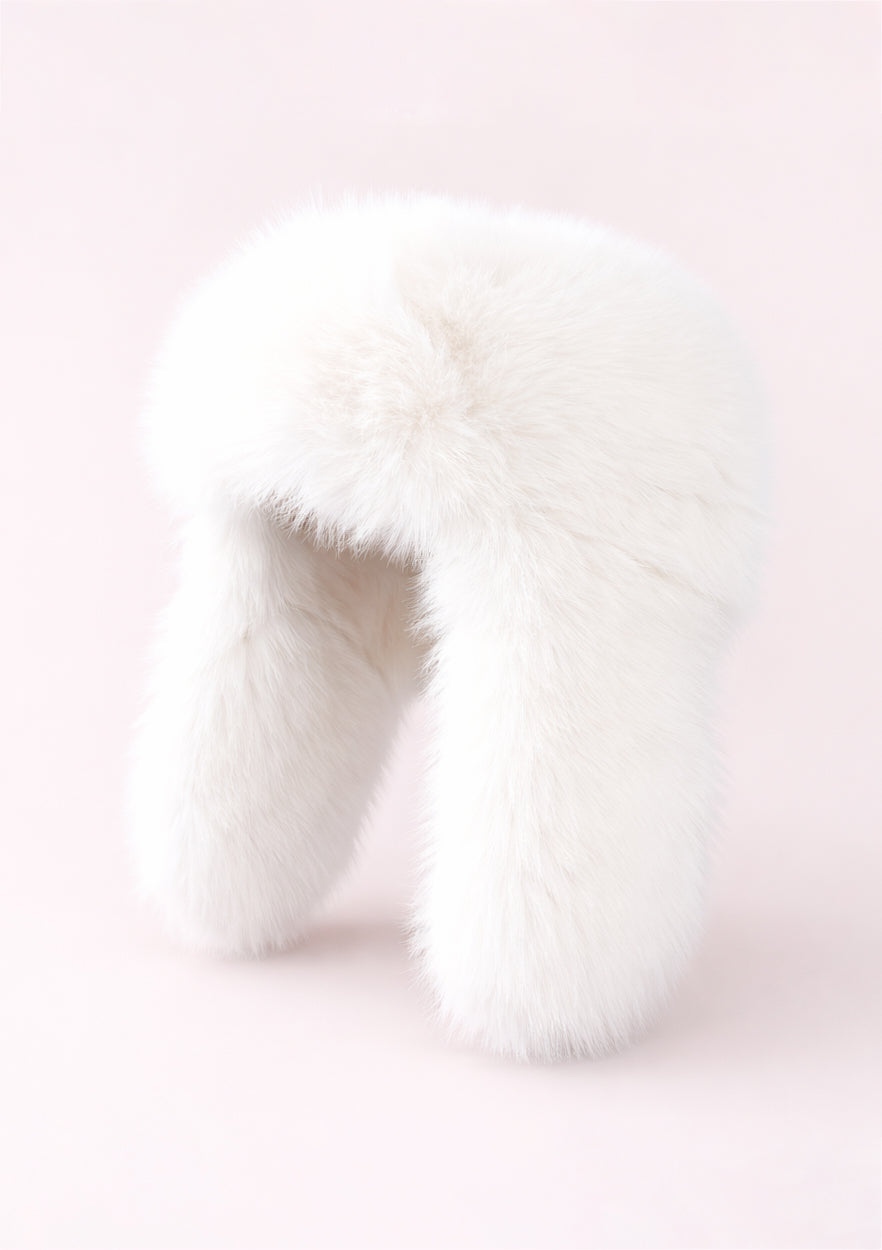 Close-up of white fur hat on a light pink background