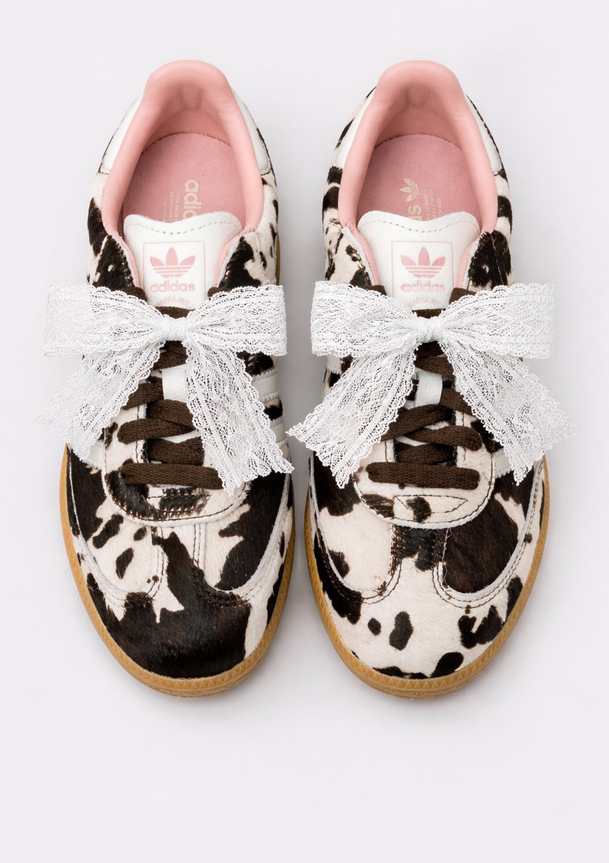 Cow print sneakers with white lace bows shoe charm on a white background