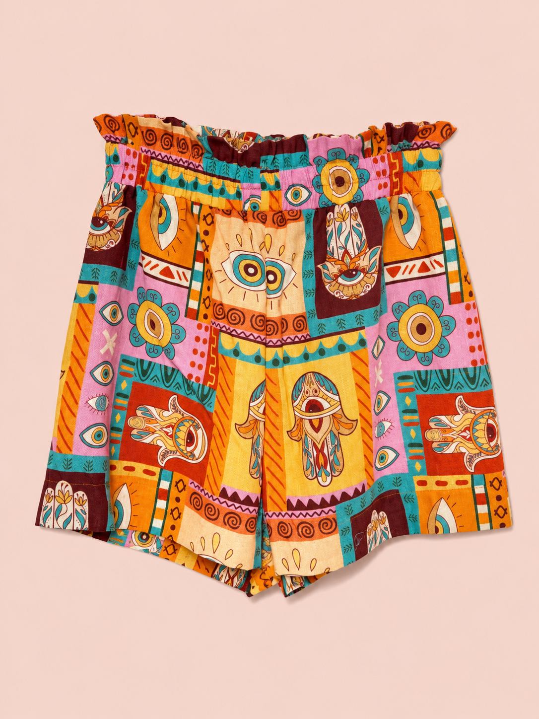 A pair of women's shorts featuring a vibrant, multicolored bohemian patchwork print with eye and tribal motifs, set against a solid pale pink background.
